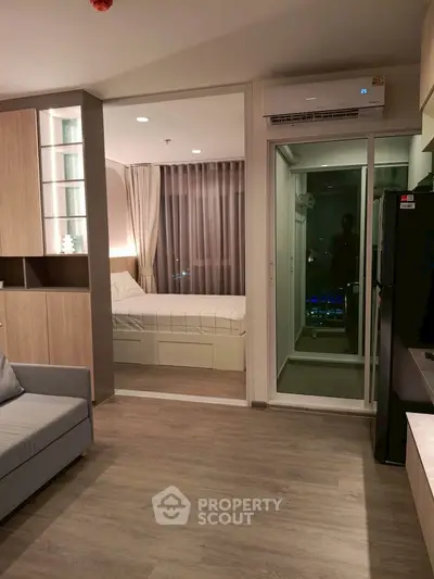 Modern apartment interior with cozy living room and stylish bedroom separated by glass doors.