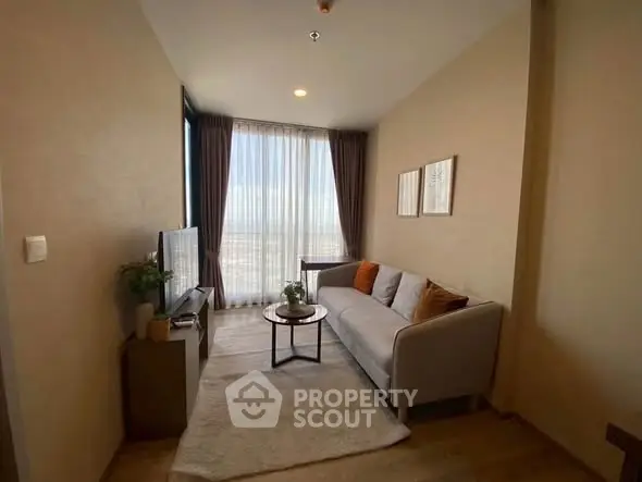 Cozy living room with modern decor and large window offering stunning city views.