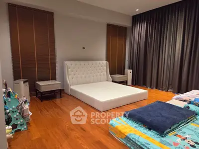 Spacious bedroom with elegant wooden flooring and modern furnishings, featuring a stylish bed and cozy ambiance.