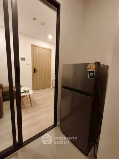 Modern apartment interior with sleek fridge and cozy living area