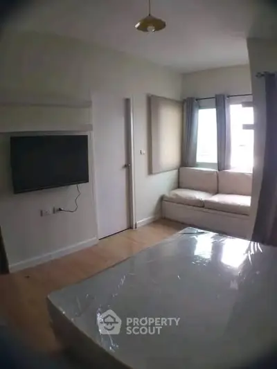 Cozy bedroom with wall-mounted TV and natural light from large window.