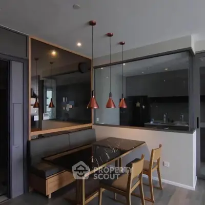 Modern dining area with sleek black table, pendant lights, and open kitchen layout.