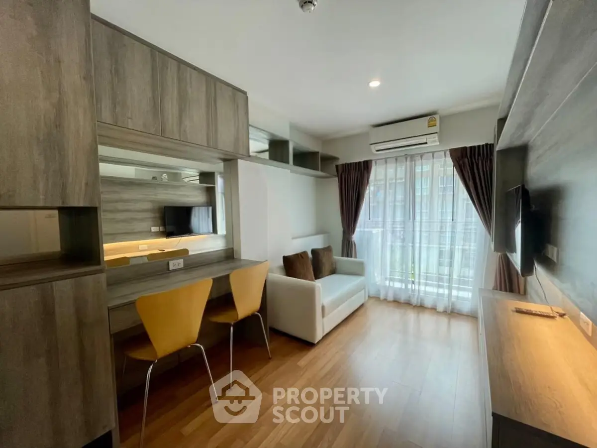 Modern living room with wooden flooring, cozy sofa, and large window for natural light.