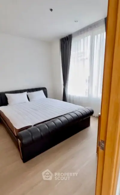Spacious bedroom with elegant bed and large window for natural light