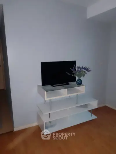 Minimalist living room with modern TV stand and decorative vase on wooden floor.