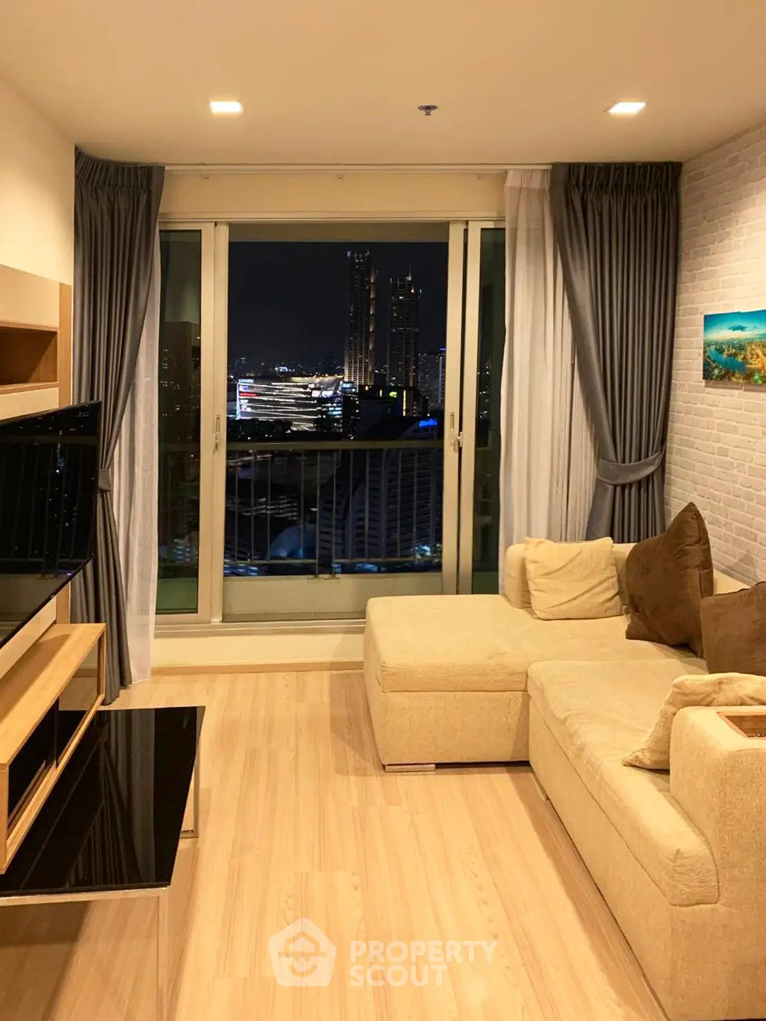 Stylish living room with city view, cozy beige sofa, and modern decor in high-rise apartment.