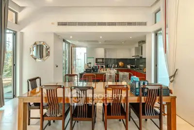Spacious dining area with elegant wooden table and modern kitchen in open layout design.