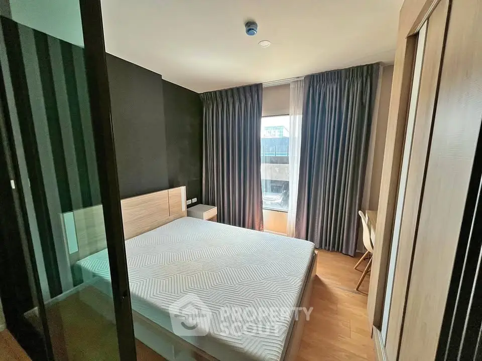 Modern bedroom with large window and wooden flooring in stylish apartment.