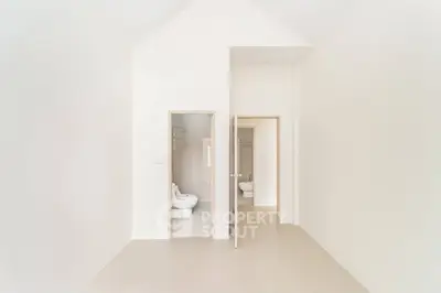 Minimalist bathroom with sleek white fixtures and open door design