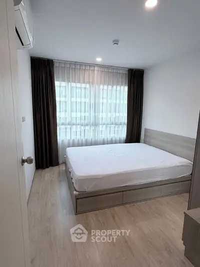 Modern bedroom with large window and minimalist design in urban apartment.