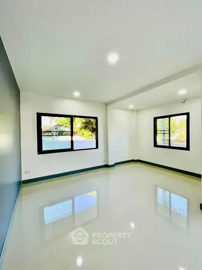 Spacious and bright living room with large windows and glossy tiled floors.