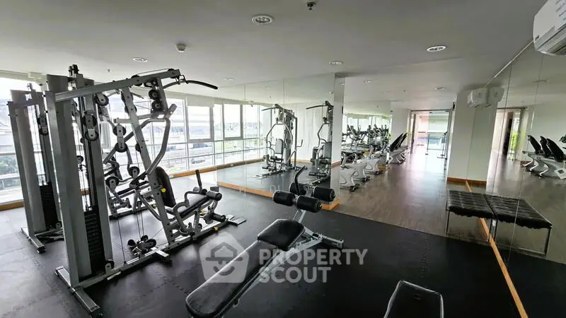 Spacious modern gym with state-of-the-art equipment and large windows for natural light.
