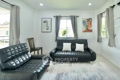 Modern living room with stylish black leather sofas and abstract art on white walls.