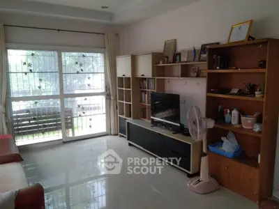 Spacious living room with large window and modern shelving unit.