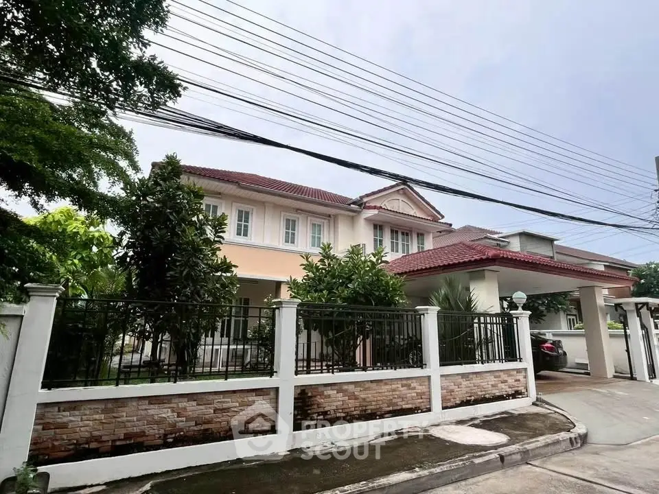 Charming two-story house with red-tiled roof and lush greenery in a serene neighborhood.