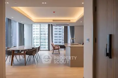 Spacious modern living room with open kitchen and city view, featuring elegant dining area and stylish decor.
