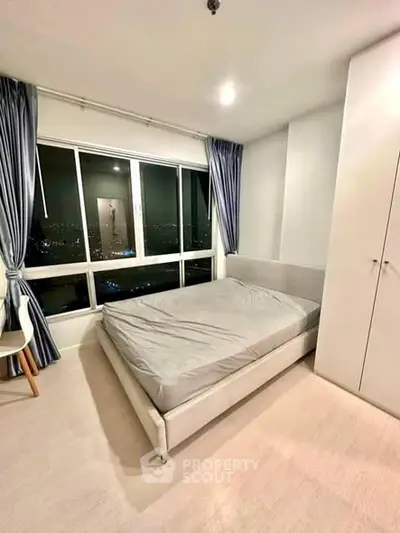 Modern bedroom with city view, featuring sleek design and ample natural light.