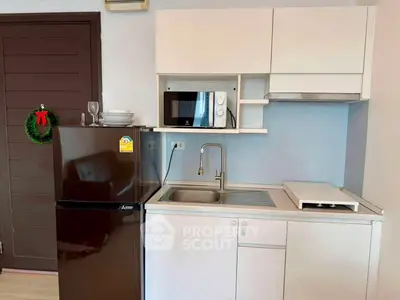 Compact kitchen with modern appliances and sleek cabinetry in a cozy apartment setting.