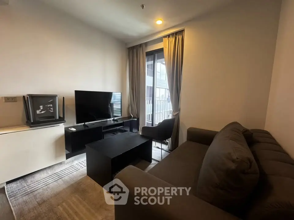 Cozy living room with modern sofa and flat-screen TV, perfect for relaxation.