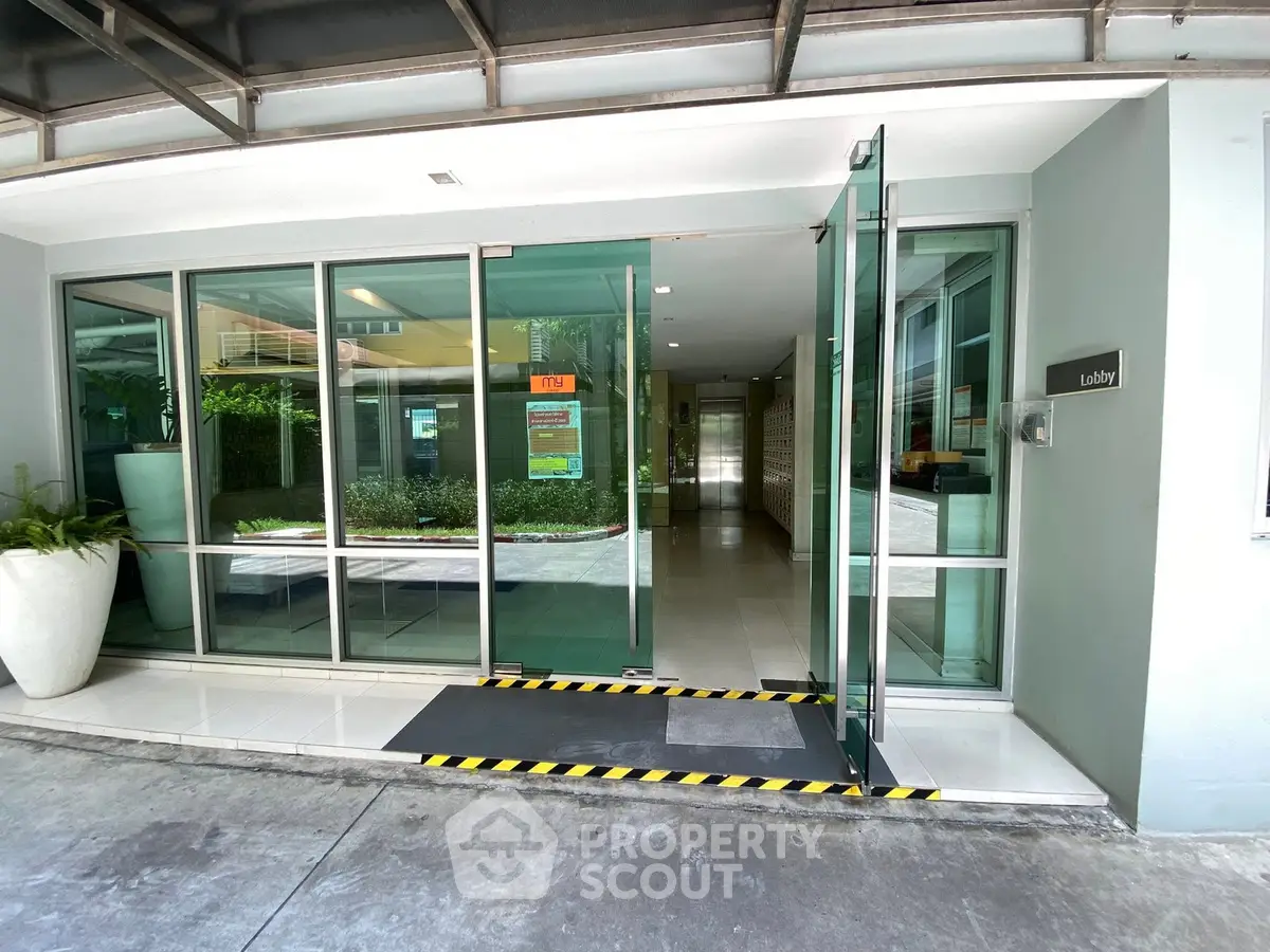 Modern building entrance with glass doors and sleek design, inviting lobby area with natural light.