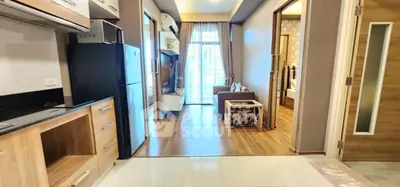 Modern open-plan apartment with stylish kitchen and cozy living area, featuring wooden flooring and natural light.