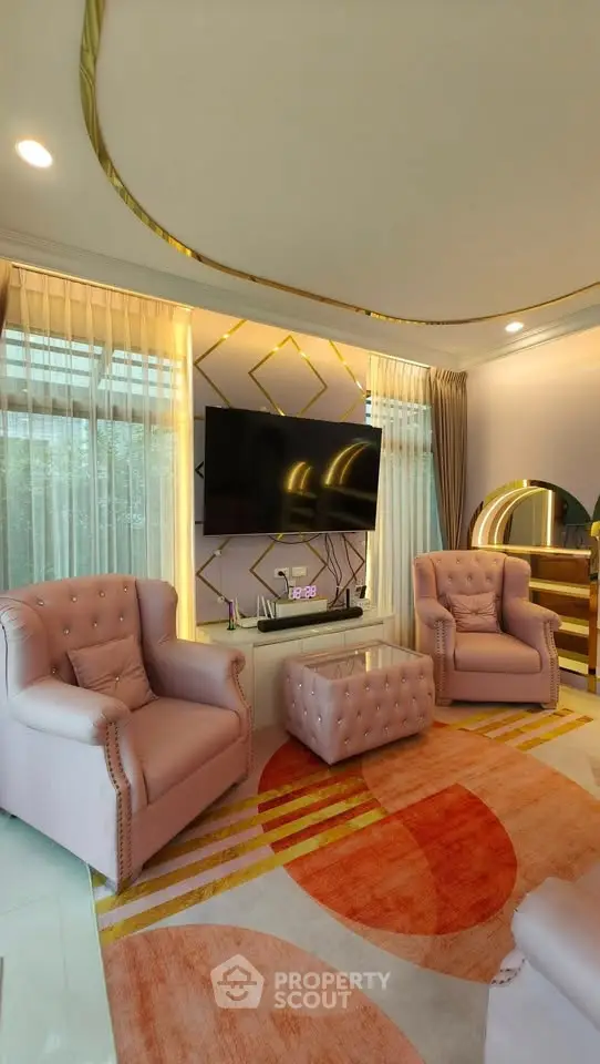 Luxurious living room with elegant decor, featuring plush armchairs, a large TV, and stylish lighting.