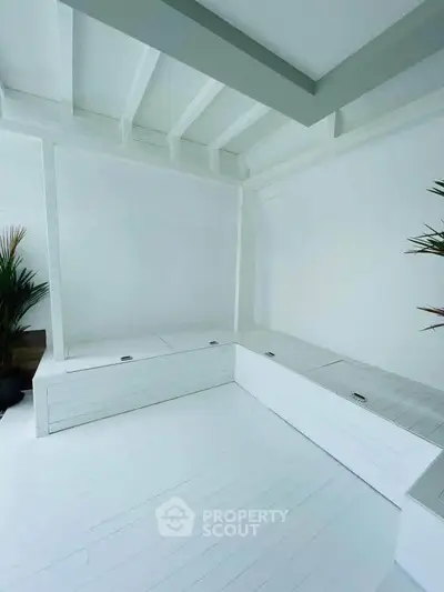 Bright white minimalist interior with built-in seating and plants, perfect for modern living.