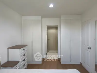 Spacious bedroom with elegant white wardrobes and wooden dresser