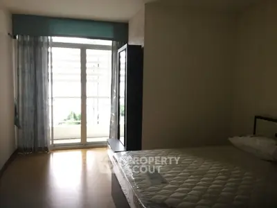 Spacious bedroom with large window and balcony access, ideal for natural light lovers.
