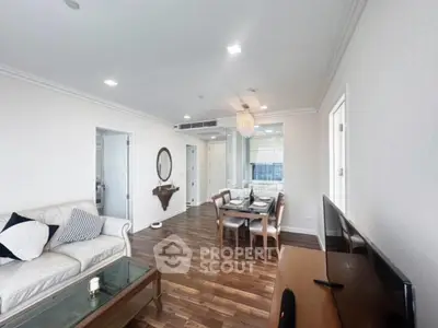 Spacious living room with elegant decor and dining area, featuring hardwood floors and modern lighting.