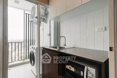 Modern kitchen with balcony view, featuring sleek cabinetry, washing machine, and microwave.