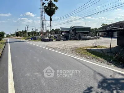 Spacious roadside property with potential for development, featuring open land and nearby infrastructure.