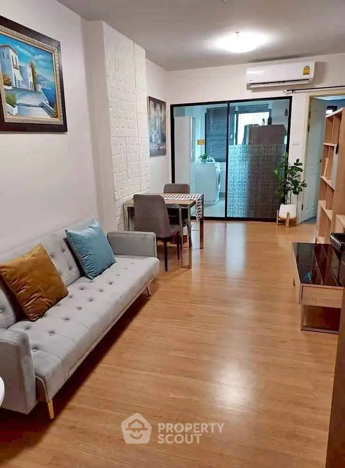 Spacious living room with modern decor and wooden flooring, featuring a cozy sofa and dining area.