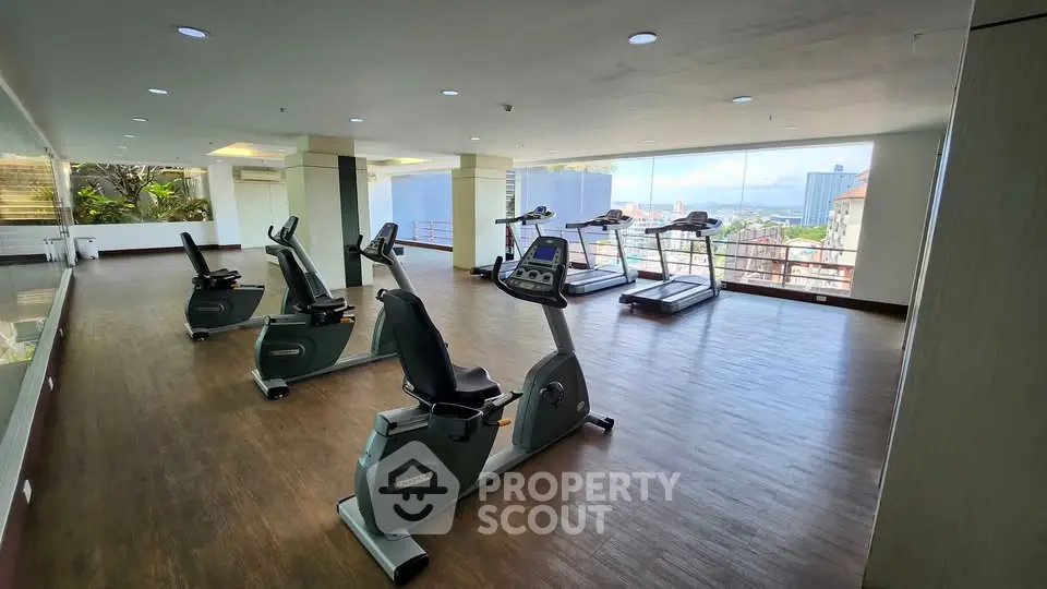 Spacious gym with modern equipment and panoramic city views, perfect for fitness enthusiasts.