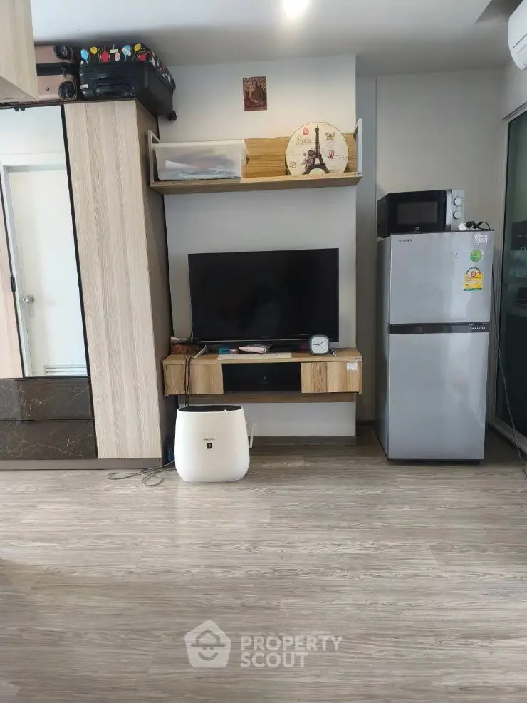 Modern living room with TV, fridge, and stylish wooden flooring