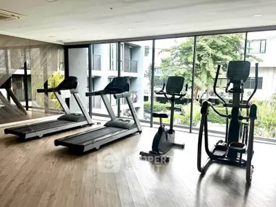 Modern gym with treadmills and exercise bike in a bright, spacious room with large windows.