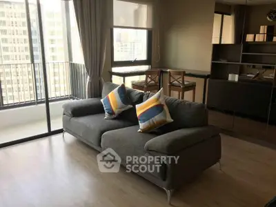 Modern living room with stylish sofa and large windows offering city views.