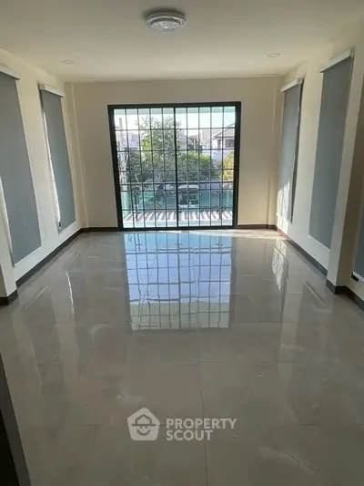 Spacious sunlit room with large windows and glossy tiled floor, perfect for modern living.