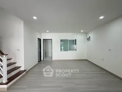Spacious modern living room with sleek flooring and staircase, perfect for contemporary living.