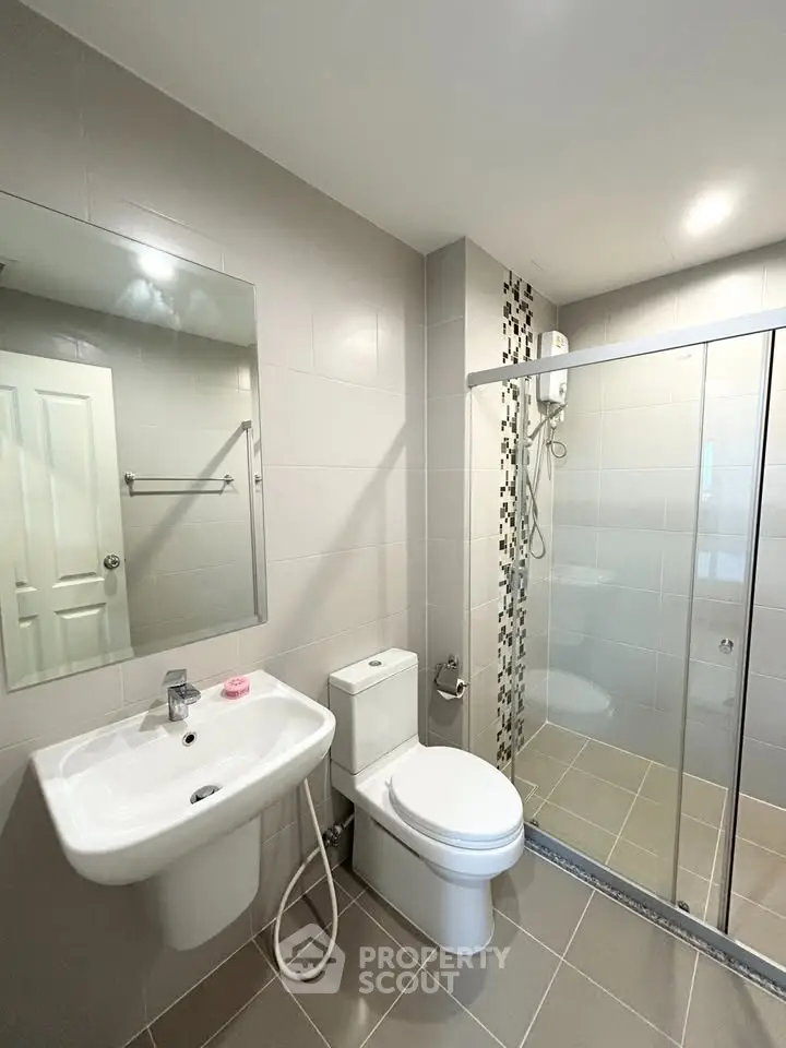 Modern bathroom with sleek design, featuring a glass shower enclosure and stylish fixtures.