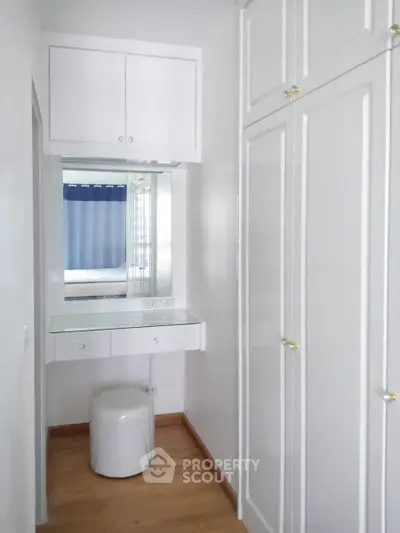Elegant white storage area with built-in cabinets and vanity mirror