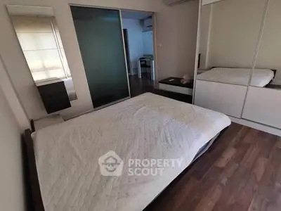 Spacious bedroom with wooden flooring and mirrored wardrobe in modern apartment.