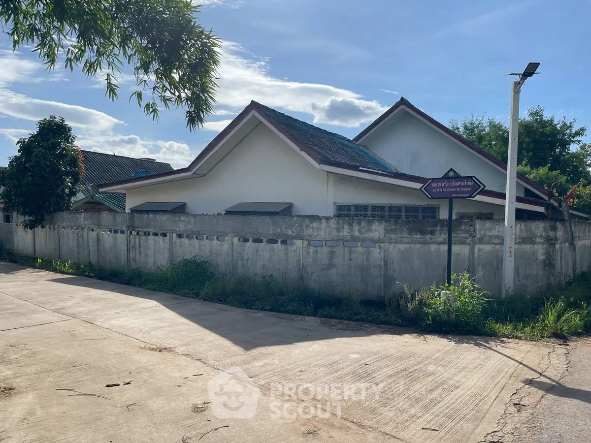 Charming suburban house with sloped roof and surrounding wall, ideal for family living.