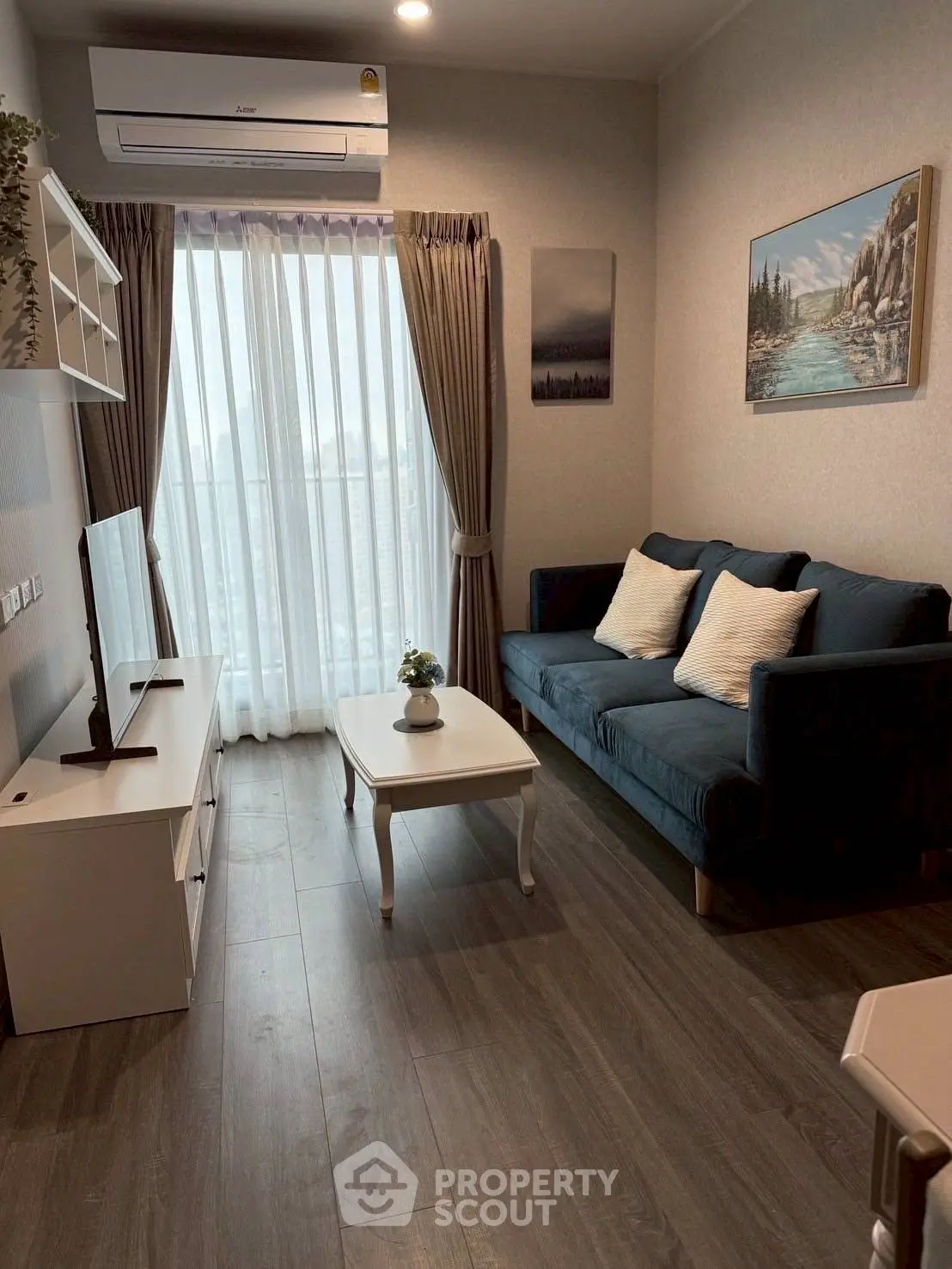 Charming living room with cozy sofa and natural light through large window.