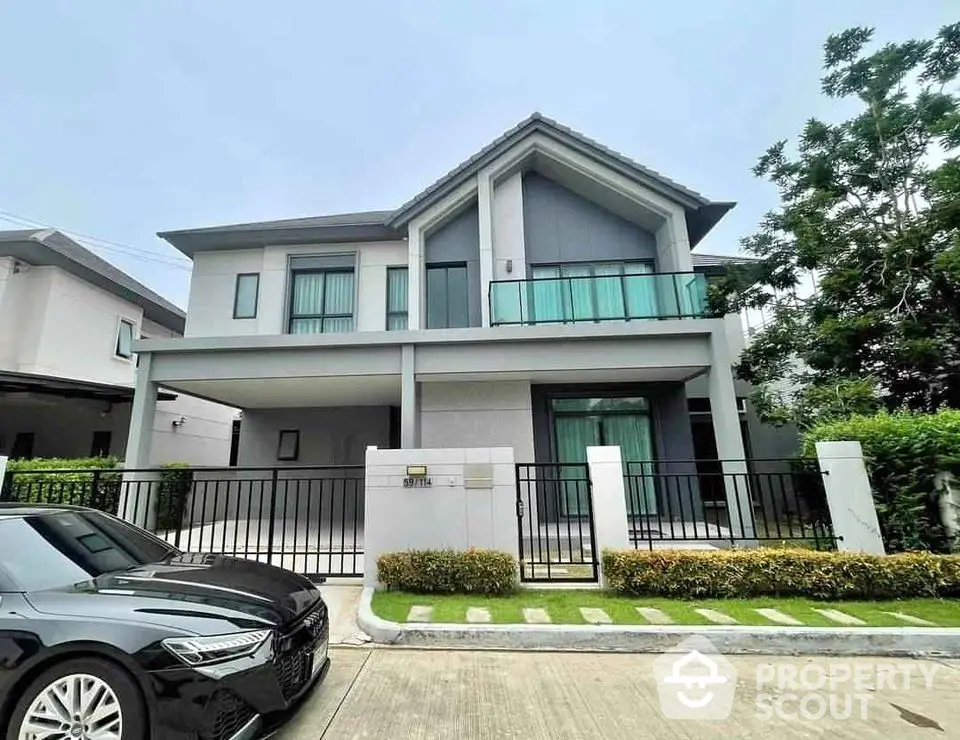 Modern two-story house with sleek design and spacious driveway in a suburban neighborhood.