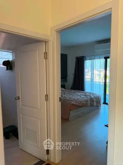 Cozy bedroom with natural light and adjacent bathroom, featuring modern decor and a serene atmosphere.