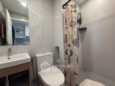Modern bathroom with stylish tiles and floral shower curtain in a contemporary apartment.