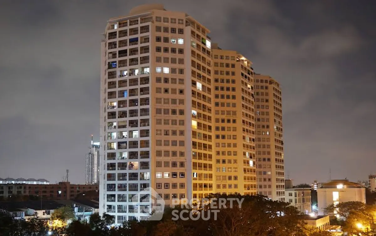 Stunning night view of a modern high-rise residential building with illuminated windows and urban skyline.