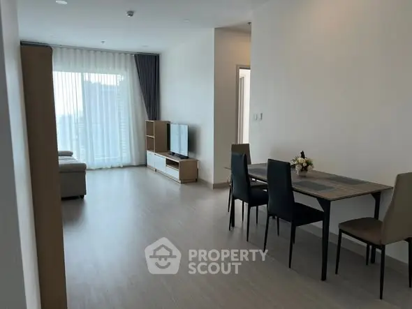 Modern living room with dining area and large window in a stylish apartment.