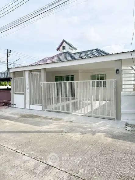 Charming single-story house with gated entrance and modern roof design.